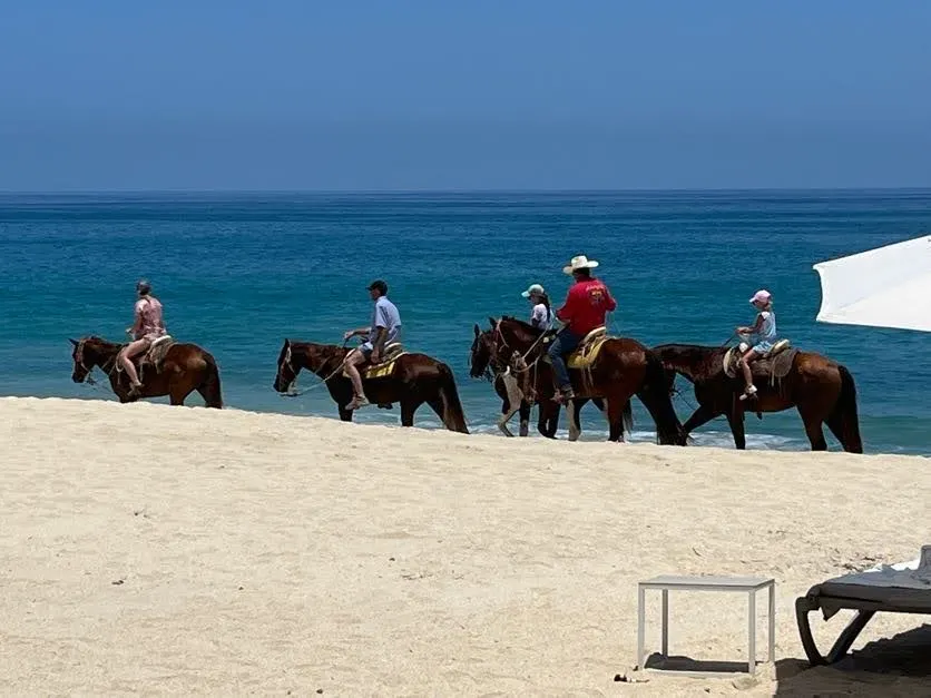 Gente montando a caballo en la playa.