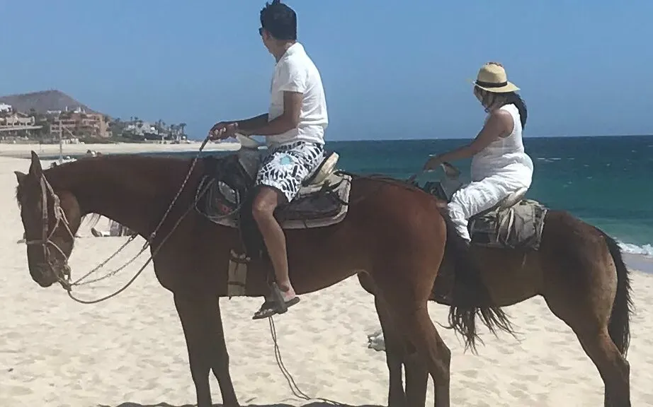 Imagen de una pareja montando a caballo en la playa.