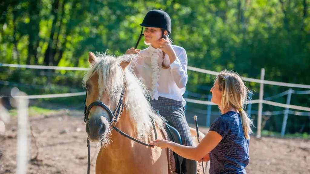 Imagen de una niña recibiendo clases de equitación.